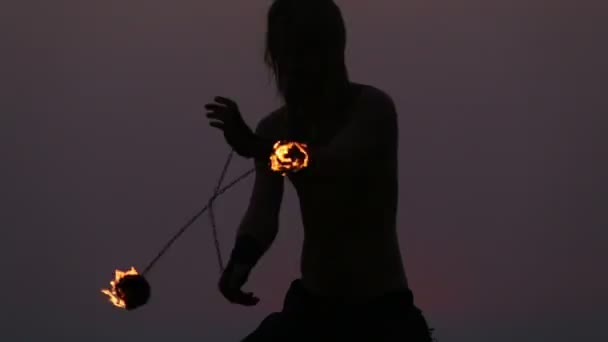 Male Artist of the spins fire poi on a rock — Stock Video