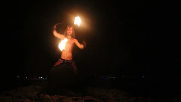 Male Artist of the spins fire poi on rock — Stock Video