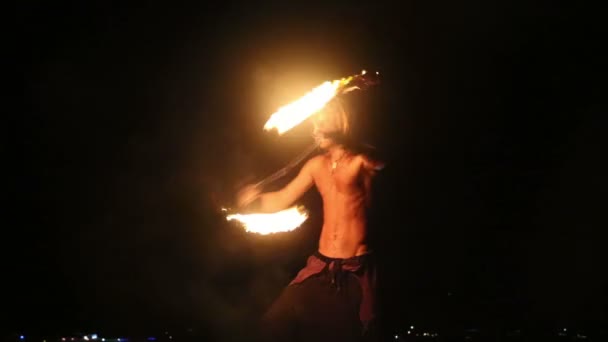 Мужчина-артист крутит огненный пои на камне — стоковое видео
