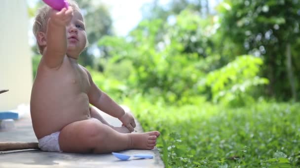 Niño jugar sentado en el patio — Vídeos de Stock