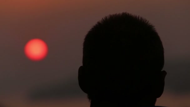Człowiek podziwia zachód słońca nad morzem — Wideo stockowe
