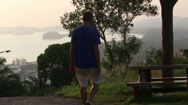 Hombre mira el atardecer en el mar — Vídeo de stock