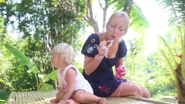 Madre soplando burbujas para hija — Vídeo de stock