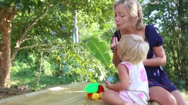 Madre soplando burbujas para hija — Vídeo de stock