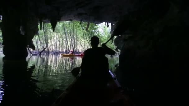 Hombre remando kayak fuera de la gruta — Vídeos de Stock