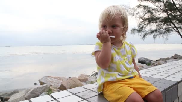 Niño comiendo galletas en primera línea de mar — Vídeos de Stock