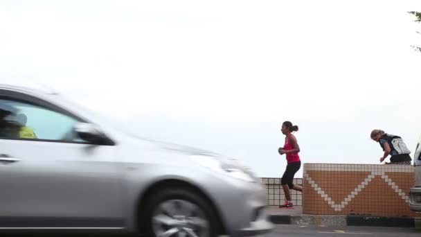 Les gens jogging le long de la route de la ville — Video