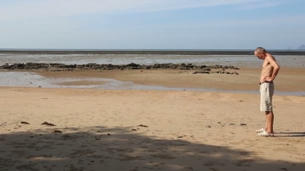 Vieil homme faisant du yoga sur la plage — Video