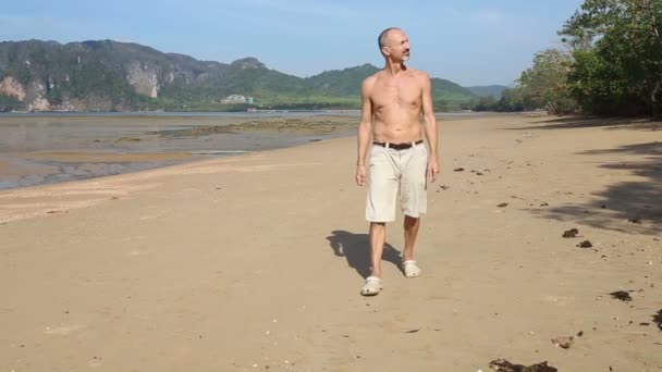 Velho caminhando ao longo da praia — Vídeo de Stock