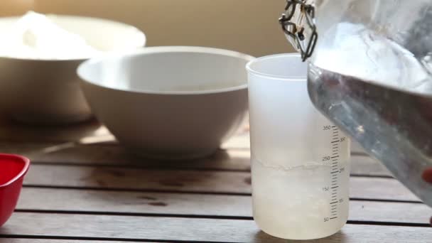 Mujer vertiendo agua en taza de medir — Vídeos de Stock