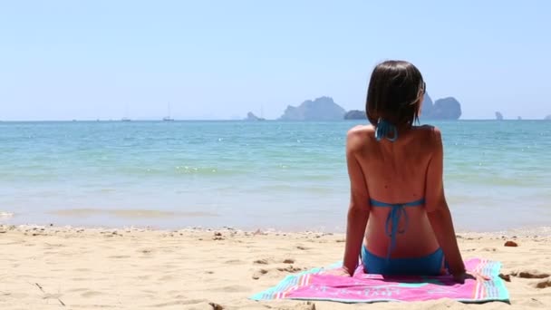 Chica joven sentada en la playa — Vídeos de Stock