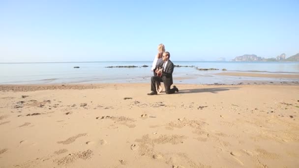 Мужчина с гитарой и девушка на пляже — стоковое видео
