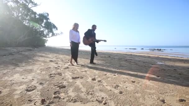 Man met gitaar en meisje op strand — Stockvideo