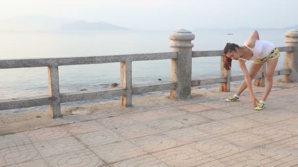 Азиатская девушка растянувшаяся на набережной — стоковое видео