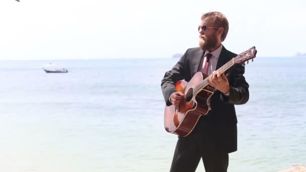 Человек играет на гитаре в море — стоковое видео