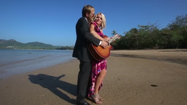 Mujer y hombre con guitarra en la playa — Vídeo de stock