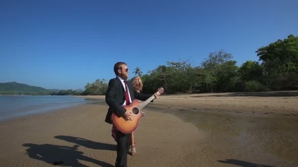 Vrouw en man met gitaar op strand — Stockvideo