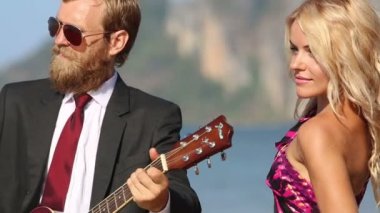 Kız ve adam sahilde gitar ile