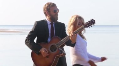 Kız ve adam sahilde gitar çalmak