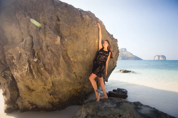 Woman in lace dress stands by rock — Stockfoto