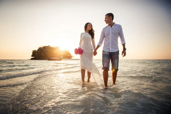 Bride and groom walk  in shallow water — Stock Photo, Image