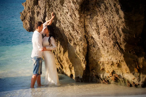 Bride and groom lean on rock — Stock Photo, Image