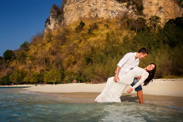 Groom holds bride in arms in water — Stock Photo, Image