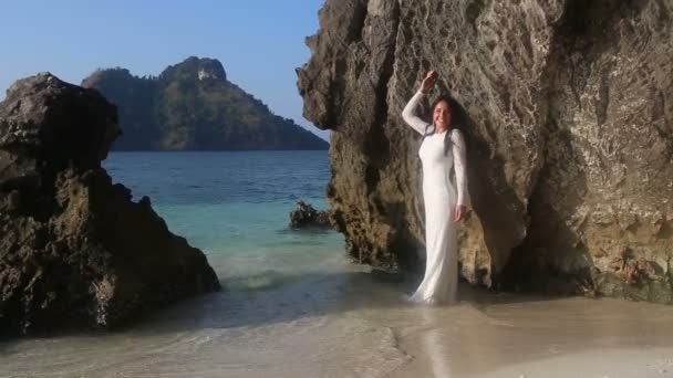 Mariée se tient dans l'eau transparente et se penche sur la roche — Video