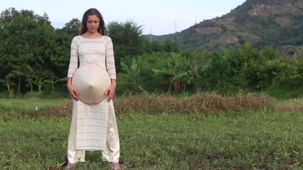 Chica en vestido vietnamita sostiene sombrero — Vídeo de stock