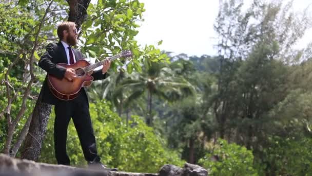 Гитарист в черном играет на гитаре и поет — стоковое видео