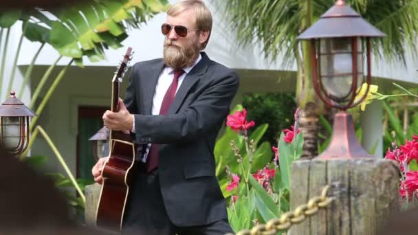 Skäggig man i svart kostym spelar gitarr — Stockvideo