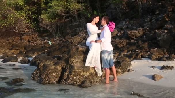 Bride sits on rock  and groom holds hands — Stock Video