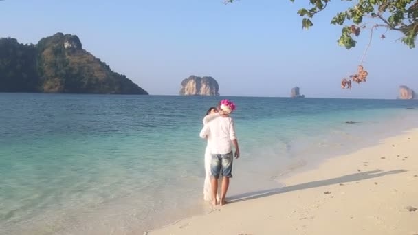 Bride and groom walk barefoot on beach — Stock Video