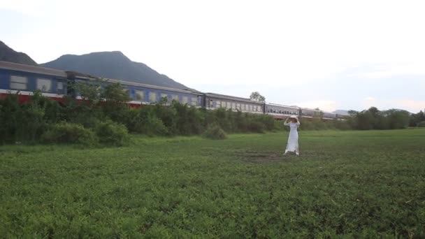 Menina em poses vietnamitas no vale contra trem — Vídeo de Stock