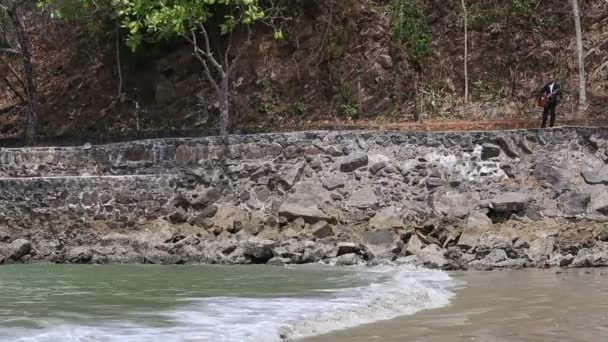 Guitarist plays guitar walking rocky embankment — Stock Video