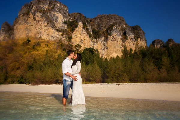 Bride and groom  in water near cliffs — Stock Photo, Image