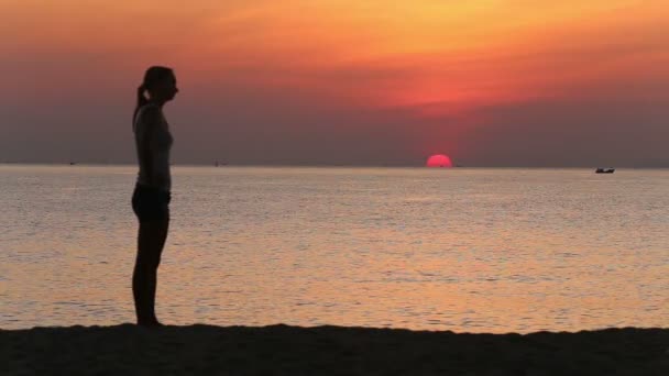 Woman doing exercises on beach at sunrise — ストック動画