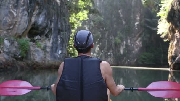 Old man paddles among sunlit cliffs — Stock Video