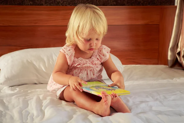 Meisje op de sofa en boek — Stockfoto