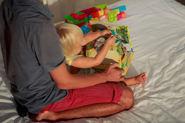 Klein meisje en vader kijken naar boek — Stockfoto