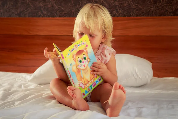 Menina no sofá e livro — Fotografia de Stock