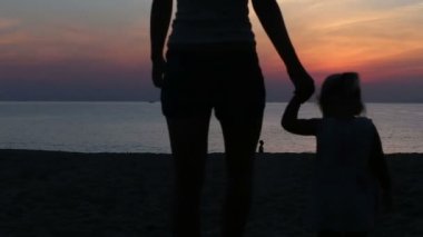 Anne ve kızı güneş doğarken denize gidiyor