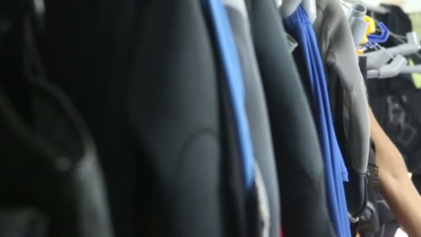 Мужчина выбирает костюм для дайвинга на вешалке — стоковое видео