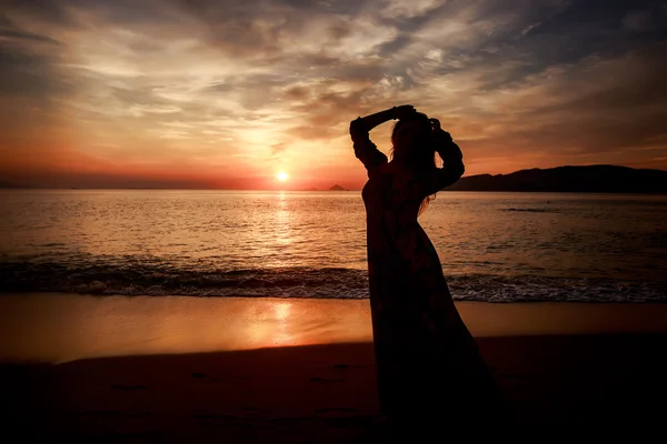 Girl in long against sunrise over sea — Stock Photo, Image