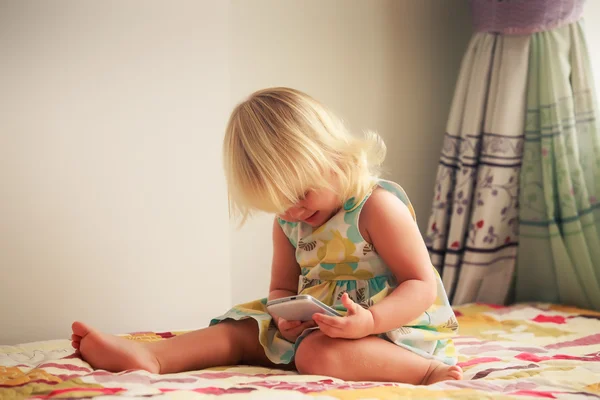 Blond meisje speelt met smartphone — Stockfoto