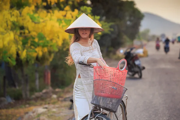 Девушка во вьетнамском платье рядом с велосипедом — стоковое фото