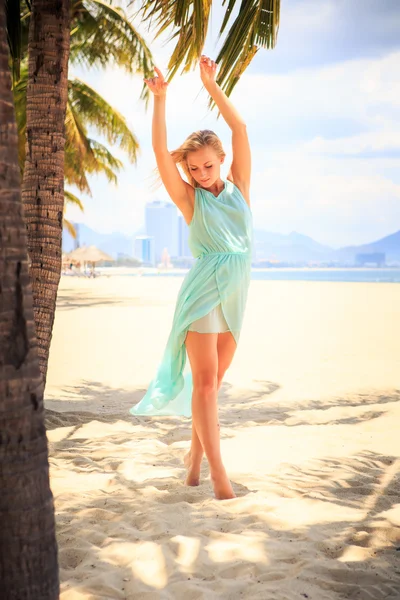 Blonde girl in azure looks  on beach — Stok fotoğraf