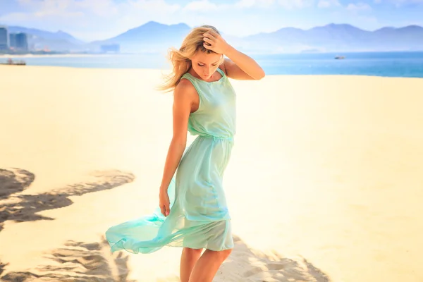 Блондинка в прозрачном платье на пляже — стоковое фото