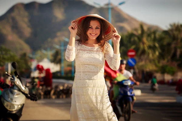 Девушка во вьетнамском платье касается шляпы — стоковое фото