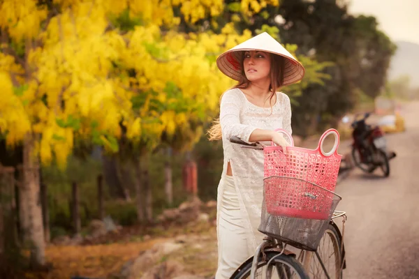 Девушка на вьетнамском языке и шляпа на велосипеде — стоковое фото